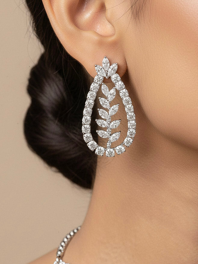 Close-up of a women wearing an ornate Indo-Western American Diamond Silver Layered Collar jewellery set and earrings with American Diamond. Close-up of a cocktail party look featuring a premium American diamond necklace. Party wear outfit completed with a lightweight American diamond necklace.