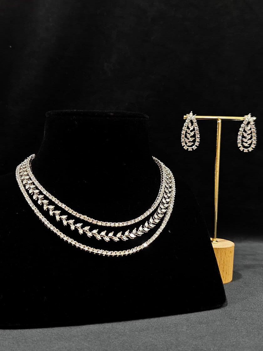 Close-up of an ornate Indo-Western American Diamond Silver Layered Collar jewellery set and earrings with American Diamond. Close-up of a cocktail party look featuring a premium American diamond necklace. Party wear outfit completed with a lightweight American diamond necklace.