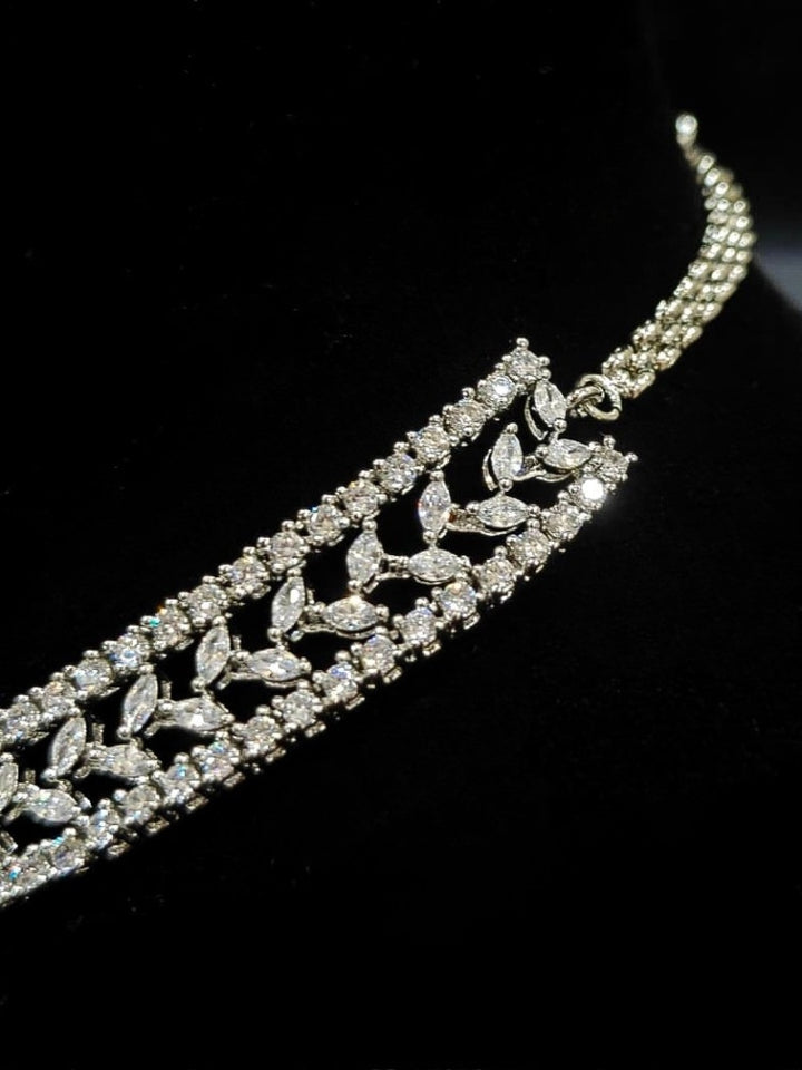 Close-up of an ornate Indo-Western American Diamond Silver Layered Collar jewellery set and earrings with American Diamond. Close-up of a cocktail party look featuring a premium American diamond necklace. Party wear outfit completed with a lightweight American diamond necklace.