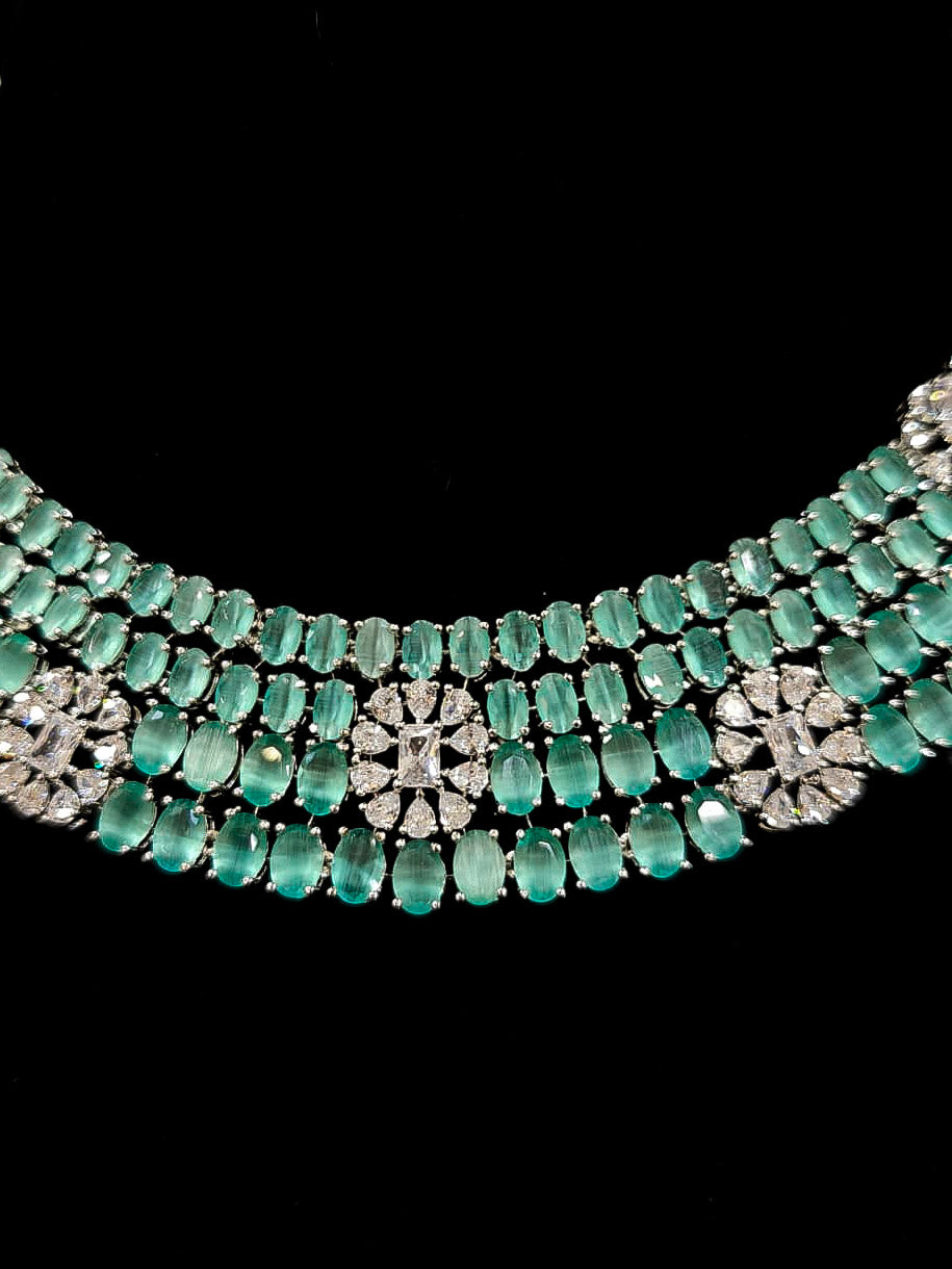 "An exquisite artificial diamond necklace with mint green colored stone and matching earrings, designed for the perfect engagement look. This stunning artificial diamond jewelry set offers luxury and sophistication while being an affordable alternative to natural diamonds." Reception-ready look featuring a statement American diamond jewelry set.