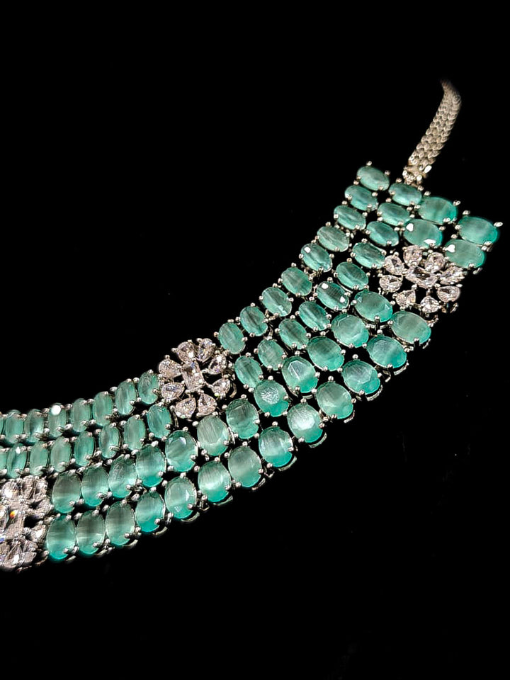"An exquisite artificial diamond necklace with mint green colored stone and matching earrings, designed for the perfect engagement look. This stunning artificial diamond jewelry set offers luxury and sophistication while being an affordable alternative to natural diamonds." Reception-ready look featuring a statement American diamond jewelry set.