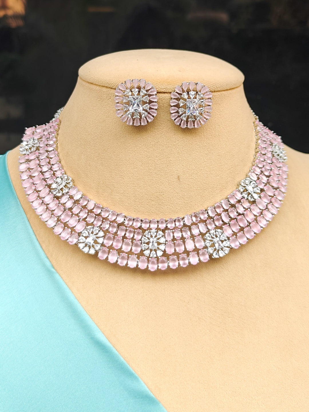 "A close-up shot of a bride wearing a stunning artificial diamond necklace with mint pink colored stone and matching earrings, designed to complement bridal attire. This affordable diamond necklace set is perfect for brides seeking luxurious but cost-effective wedding jewelry in India."
