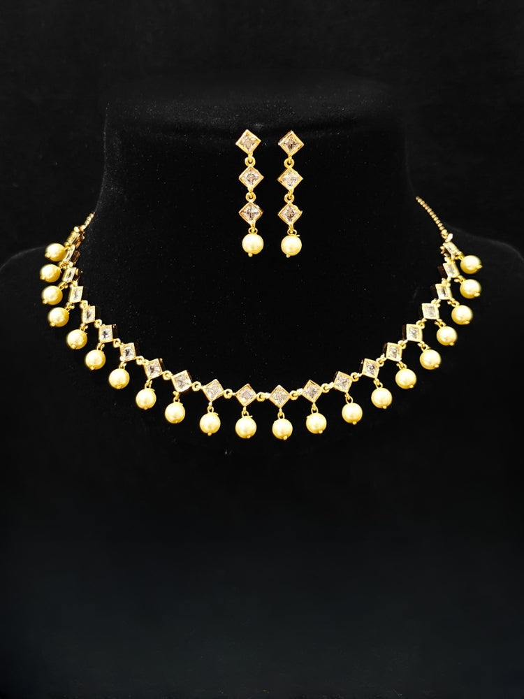 Close-up of an ornate traditional (Gold Polish) Collar jewellery set and earrings with American Diamond Polki and Pearls. Elegant festive look with a high-quality imitation American diamond necklace set. Festive Diwali outfit styled with an American diamond artificial necklace.