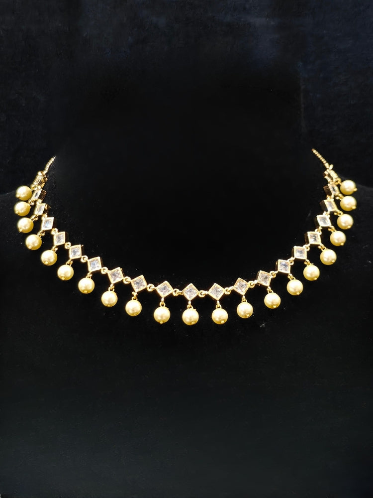 Close-up of an ornate traditional (Gold Polish) Collar jewellery set and earrings with American Diamond Polki and Pearls. Elegant festive look with a high-quality imitation American diamond necklace set. Festive Diwali outfit styled with an American diamond artificial necklace.