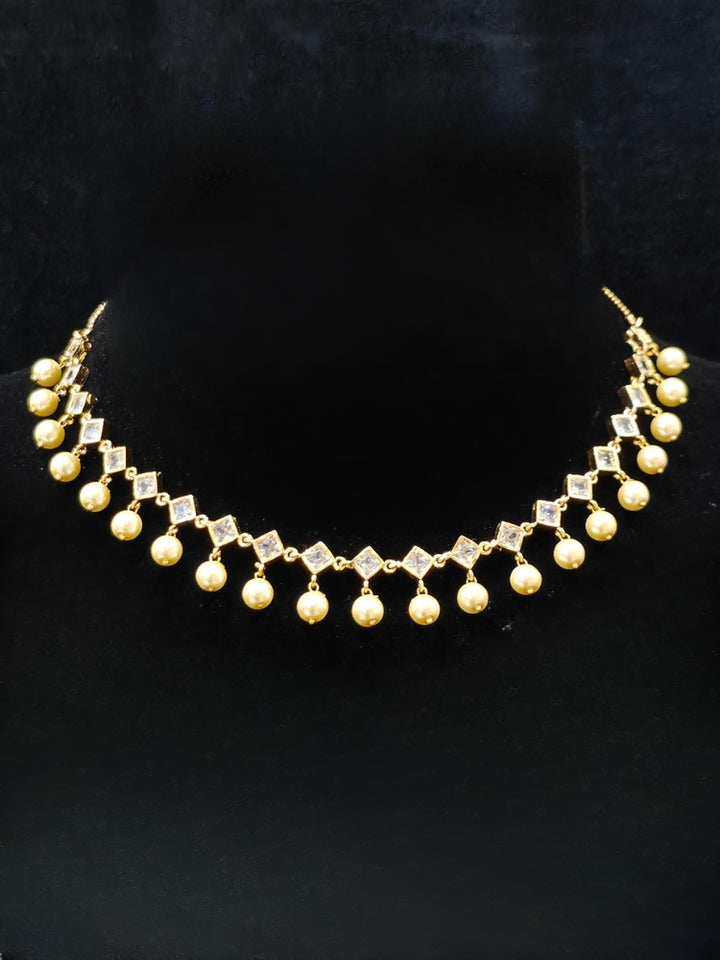 Close-up of an ornate traditional (Gold Polish) Collar jewellery set and earrings with American Diamond Polki and Pearls. Elegant festive look with a high-quality imitation American diamond necklace set. Festive Diwali outfit styled with an American diamond artificial necklace.