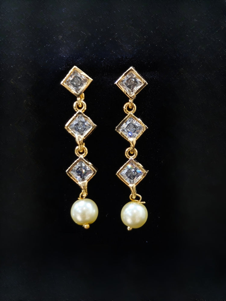 Close-up of an ornate traditional (Gold Polish) Collar jewellery set and earrings with American Diamond Polki and Pearls. Elegant festive look with a high-quality imitation American diamond necklace set. Festive Diwali outfit styled with an American diamond artificial necklace.
