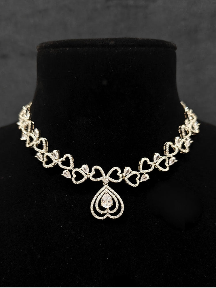 Close-up of an ornate Western (Silver Polish) Collar Diamond  jewellery set and earrings American Diamond. Reception-ready look featuring a statement American diamond jewelry set. Party wear outfit completed with a lightweight American diamond necklace.