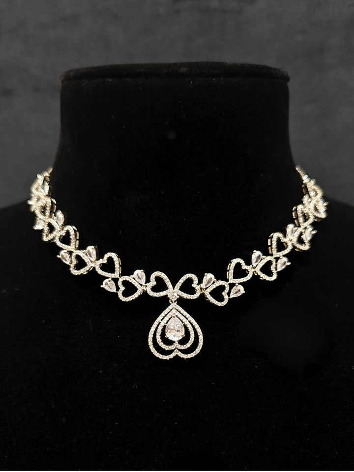 Close-up of an ornate Western (Silver Polish) Collar Diamond  jewellery set and earrings American Diamond. Reception-ready look featuring a statement American diamond jewelry set. Party wear outfit completed with a lightweight American diamond necklace.