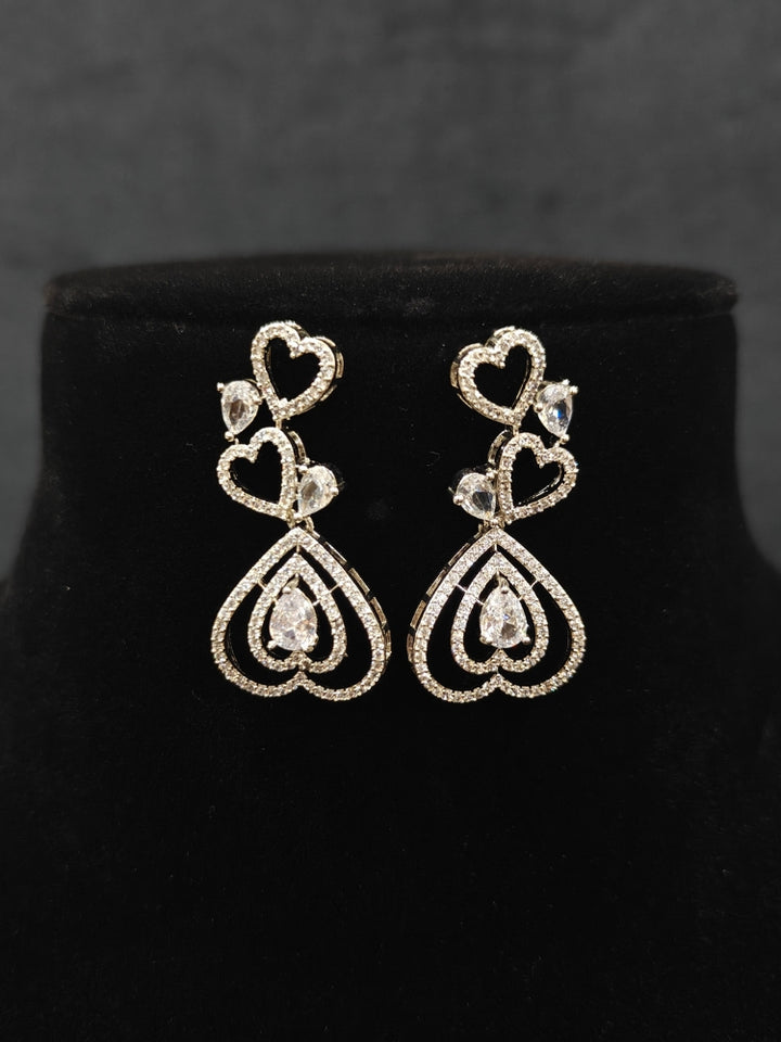 Close-up of an ornate Western (Silver Polish) Collar Diamond  jewellery set and earrings American Diamond. Reception-ready look featuring a statement American diamond jewelry set. Party wear outfit completed with a lightweight American diamond necklace.