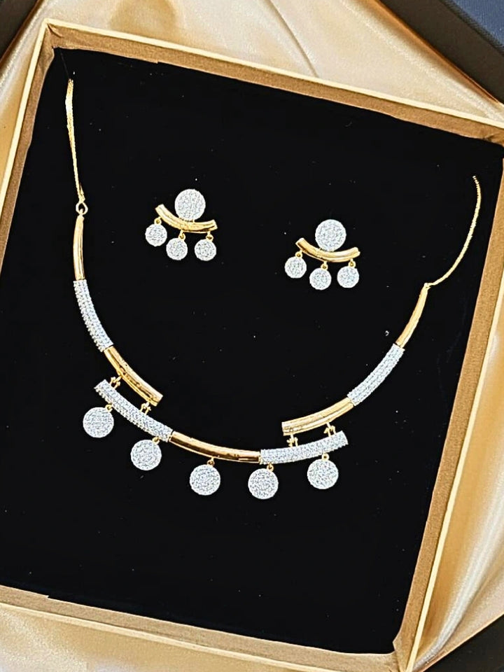 The Lunessa Necklace Set features gold and white tones with round American Diamonds, sparkling atop black velvet. This elegant accessory for cocktail gowns comes beautifully presented in a golden box.