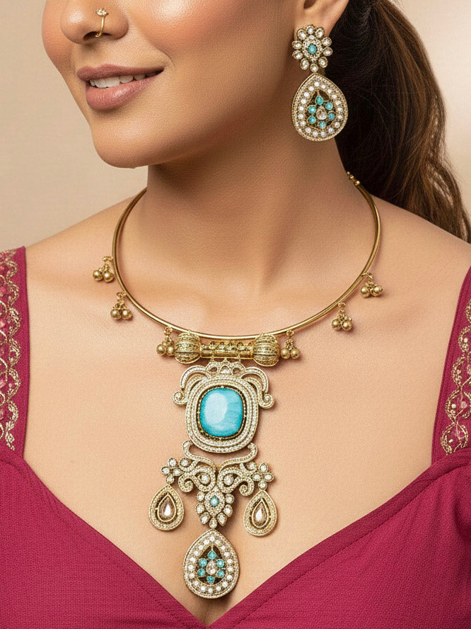 Discover the elegance of the Lupin Hasli Necklace Set, featuring a radiant Mint Blue Monalisa stone, sparkling American diamonds, and charming tiny ghungroos. Perfect for saris, weddings, and festive occasions. Put on a blue mannequin, and a beige embroidered fabric draped over the shoulder