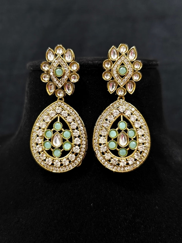 Close-up of an ornate Traditional Mint Green Diamond (Mehendi gold Polish) Hasli jewellery set and earrings with American Diamond and Mint Green Colored Stones. A luxury American diamond necklace set styled beautifully for a wedding guest look in India. Elegant festive look with a high-quality imitation American diamond necklace set.