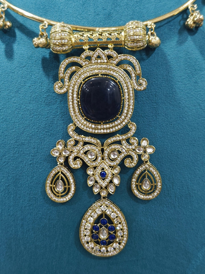 Close-up of an ornate Traditional Navy Blue Diamond (Mehendi gold Polish) Hasli jewellery set and earrings with American Diamond and Navy Blue Colored Stones. A  luxury American diamond necklace set styled beautifully for a wedding guest look in India. Elegant festive look with a high-quality imitation American diamond necklace set.