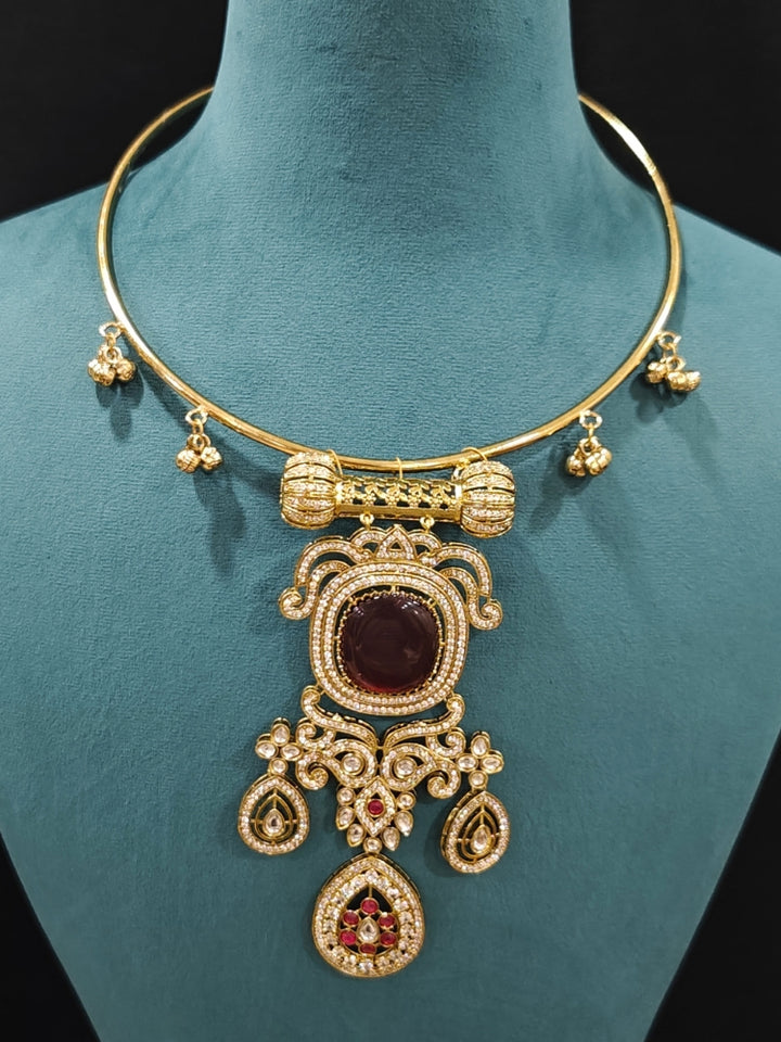 Close-up of an ornate Traditional Red Diamond (Mehendi gold Polish) Hasli jewellery set and earrings with American Diamond and Red Colored Stones. A  luxury American diamond necklace set styled beautifully for a wedding guest look in India. Elegant festive look with a high-quality imitation American diamond necklace set.
