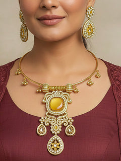 Discover the elegance of the Lupin Hasli Necklace Set, featuring a radiant Yellow Monalisa stone, sparkling American diamonds, and charming tiny ghungroos. Perfect for saris, weddings, and festive occasions. Put on a blue mannequin, and a beige embroidered fabric draped over the shoulder