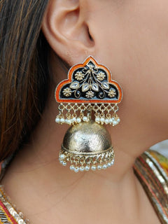 A close-up of a womans ear wearing Mackenzie Black-Orange Earrings featuring meenakari floral design, gold dome-shaped jhumka, and dangling white pearls—perfect to pair with your wedding ceremony dress.