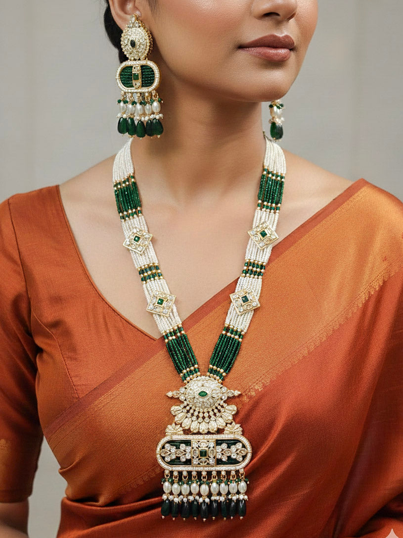 Close-up of a woman wearing an ornate traditional Green Rajwadi gold Long jewellery set and earrings  with  Pearls, Tumble Beads, Meenakari, Moissanite Kundan, Bandhai Work and Hydro Crystals. Woman wearing a Rajwadi necklace for a reception function. Elegant  look with a traditional Rajwadi artificial necklace.