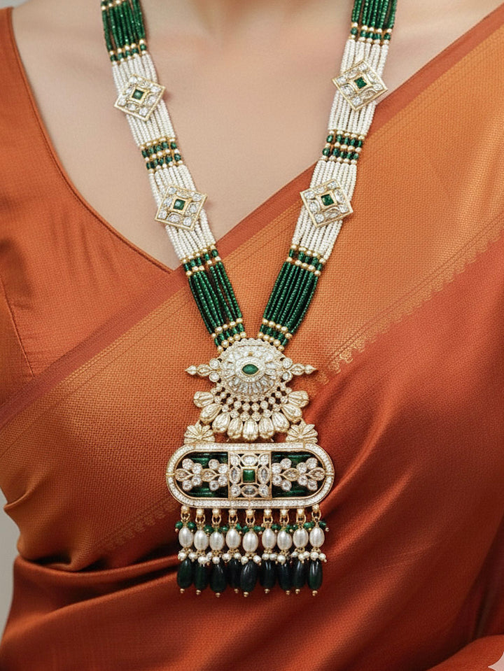 Close-up of a woman wearing an ornate traditional Green Rajwadi gold Long jewellery set and earrings  with  Pearls, Tumble Beads, Meenakari, Moissanite Kundan, Bandhai Work and Hydro Crystals. Woman wearing a Rajwadi necklace for a reception function. Elegant  look with a traditional Rajwadi artificial necklace.