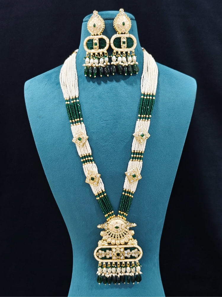 Close-up of an ornate traditional Green Rajwadi gold Long jewellery set and earrings  with  Pearls, Tumble Beads, Meenakari, Moissanite Kundan, Bandhai Work and Hydro Crystals. Close-up of detailed Rajwadi craftsmanship in artificial jewelry. Festive look completed with a luxury Rajwadi imitation necklace.