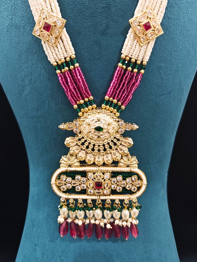 Close-up of an ornate traditional Ruby Pink and Green Rajwadi gold Long jewellery set and earrings  with  Pearls, Tumble Beads, Meenakari, Moissanite Kundan, Bandhai Work and Hydro Crystals. Woman wearing a Rajwadi necklace for a reception function. Wedding guest styling a Rajwadi artificial necklace with a Anarkali.