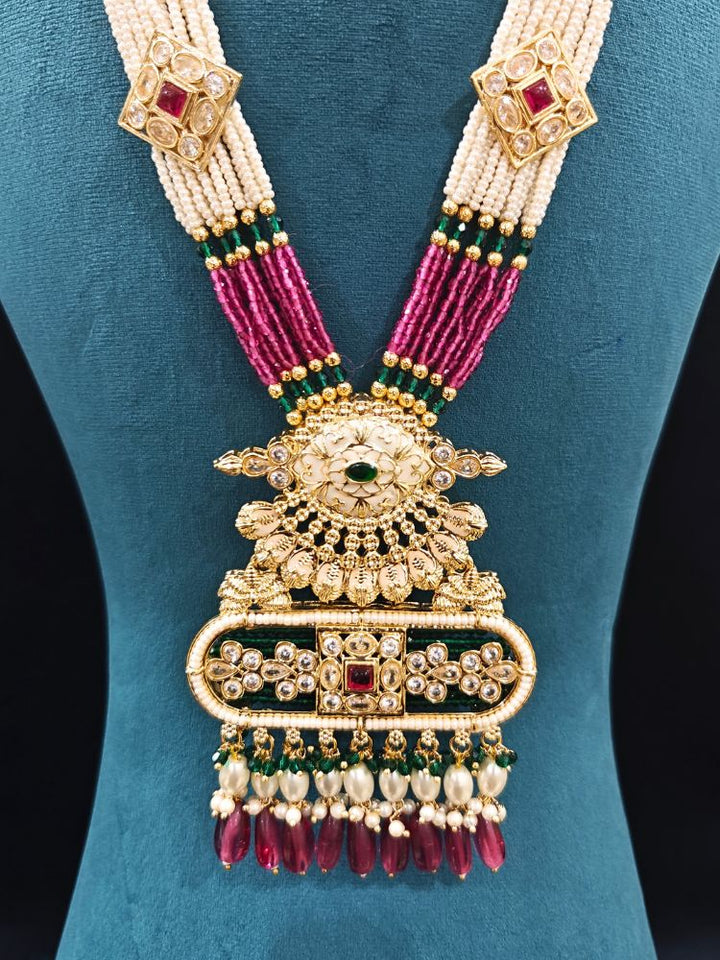 Close-up of an ornate traditional Ruby Pink and Green Rajwadi gold Long jewellery set and earrings  with  Pearls, Tumble Beads, Meenakari, Moissanite Kundan, Bandhai Work and Hydro Crystals. Woman wearing a Rajwadi necklace for a reception function. Wedding guest styling a Rajwadi artificial necklace with a Anarkali.