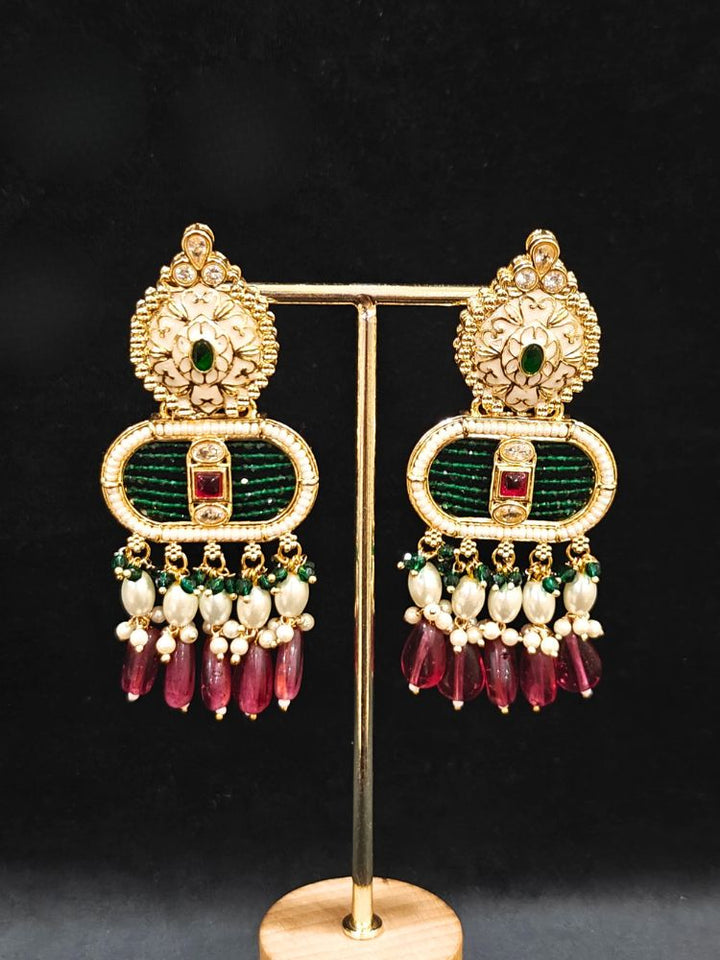Close-up of an ornate traditional Ruby Pink and Green Rajwadi gold Long jewellery set and earrings  with  Pearls, Tumble Beads, Meenakari, Moissanite Kundan, Bandhai Work and Hydro Crystals. Woman wearing a Rajwadi necklace for a reception function. Wedding guest styling a Rajwadi artificial necklace with a Anarkali.