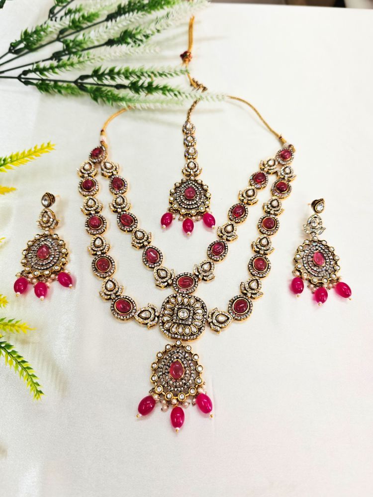 Close-up of an ornate traditional Magenta Diamond Collar Layered jewellery set and earrings and maangtikka with Kundan, American Diamonds, Tumble stones, Black Polish and Colored Stones. A luxury American diamond necklace set styled beautifully for a wedding guest look in India. Close-up of a bridal look featuring an anti-tarnish American diamond artificial necklace.