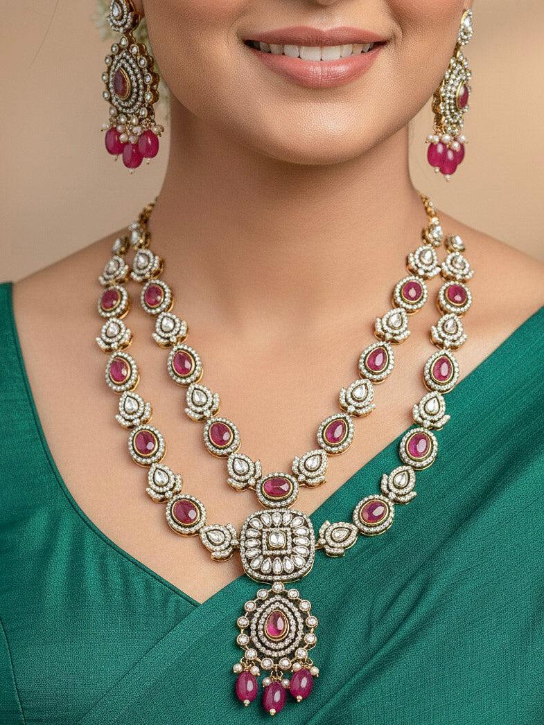 Close-up of a woman wearing an ornate traditional Magenta Diamond Collar Layered jewellery set and earrings and maangtikka with Kundan, American Diamonds, Tumble stones, Black Polish and Colored Stones. A woman wearing a luxury American diamond necklace set styled beautifully for a wedding guest look in India. Close-up of a bridal look featuring an anti-tarnish American diamond artificial necklace.