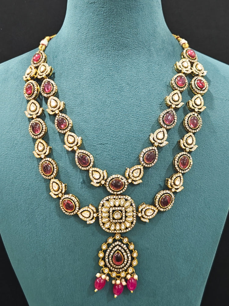 Close-up of an ornate traditional Magenta Diamond Collar Layered jewellery set and earrings and maangtikka with Kundan, American Diamonds, Tumble stones, Black Polish and Colored Stones. A luxury American diamond necklace set styled beautifully for a wedding guest look in India. Close-up of a bridal look featuring an anti-tarnish American diamond artificial necklace.