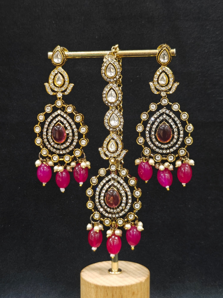 Close-up of an ornate traditional Magenta Diamond Collar Layered jewellery set and earrings and maangtikka with Kundan, American Diamonds, Tumble stones, Black Polish and Colored Stones. A luxury American diamond necklace set styled beautifully for a wedding guest look in India. Close-up of a bridal look featuring an anti-tarnish American diamond artificial necklace.