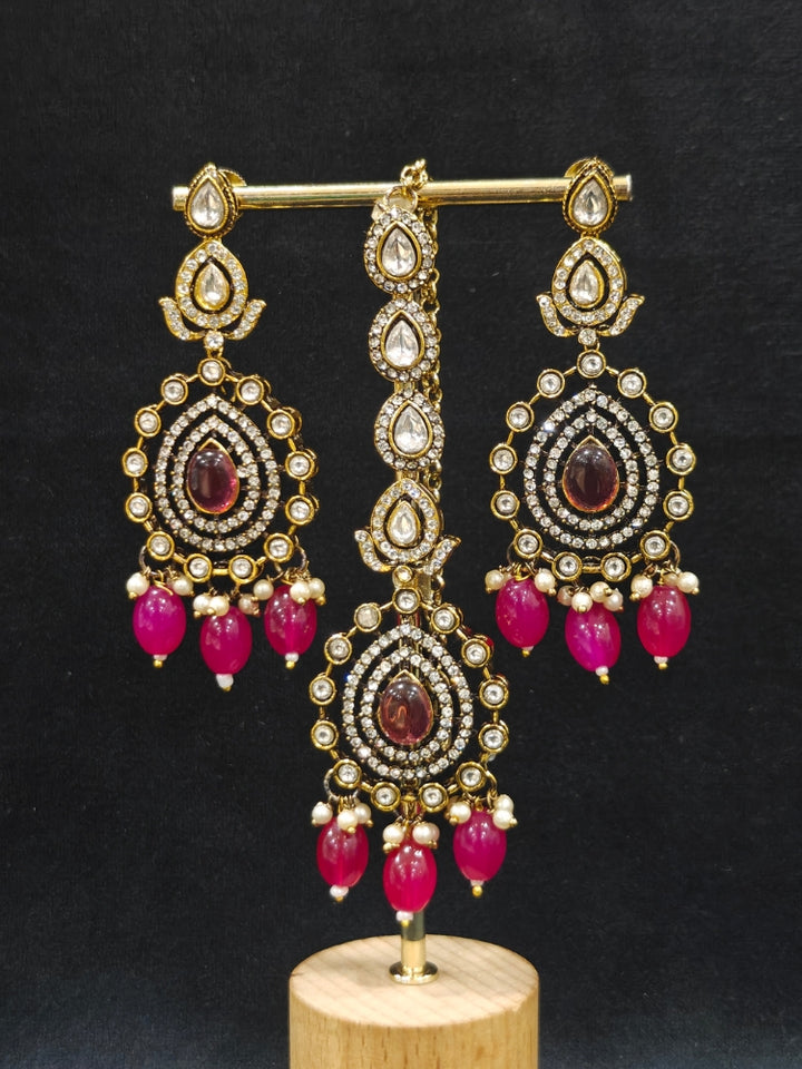 Close-up of an ornate traditional Magenta Diamond Collar Layered jewellery set and earrings and maangtikka with Kundan, American Diamonds, Tumble stones, Black Polish and Colored Stones. A luxury American diamond necklace set styled beautifully for a wedding guest look in India. Close-up of a bridal look featuring an anti-tarnish American diamond artificial necklace.