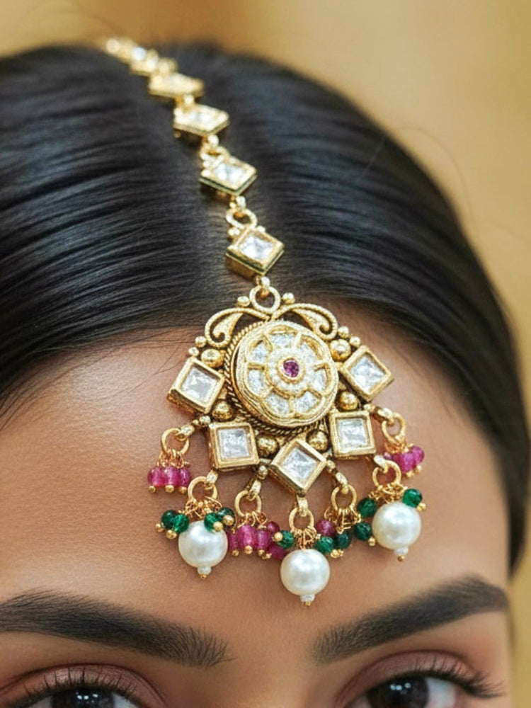 Close-up of a woman wearing an ornate traditional Rajwadi and Heritage gold Choker jewellery set and earrings and maangtikka with Pearls, Hydro Crystal and Moissanite Kundan. Bride wearing a premium Rajwadi necklace with a Lehenga for her reception. Royal bridal look completed with a statement heritage necklace set.