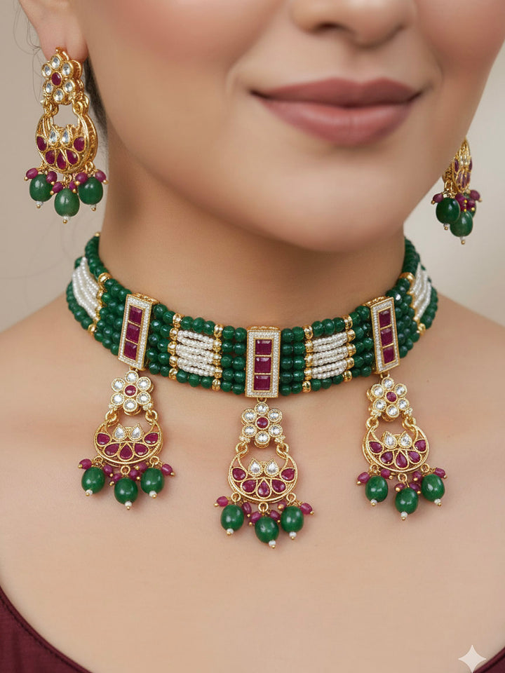 Close-up of a woman wearing an ornate traditional (Gold Polish) Green and Pink  Choker jewellery set and earrings and maangtikka with Pearls, Beads, Pink Colored Stones, Bandhai Work, Tumble Beads. Mehendi ceremony look completed with a handcrafted Colored Stone jewelry set. Woman styling a vibrant Colored Stone necklace with a festive saree.