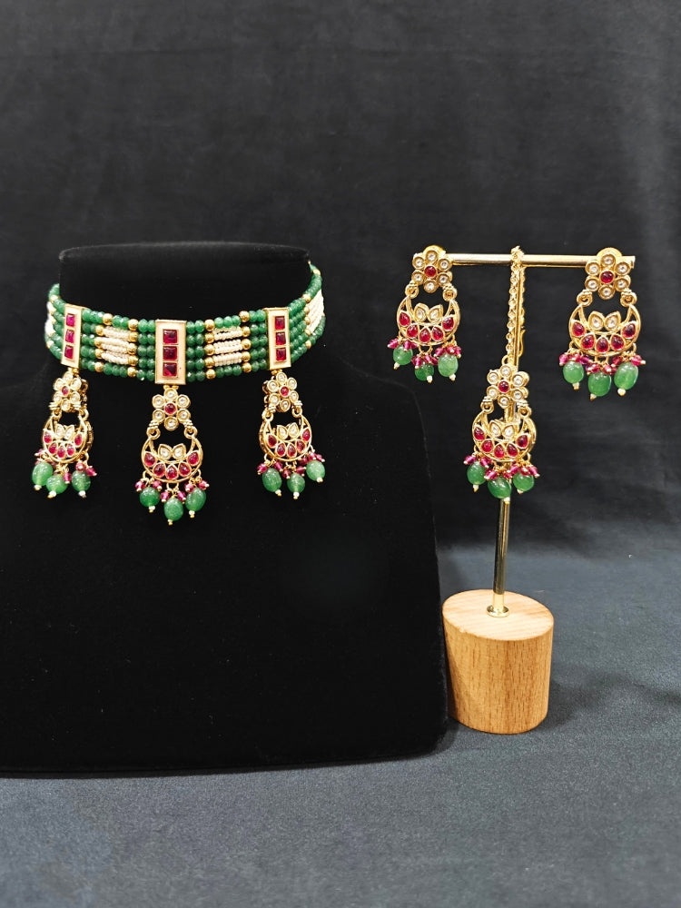 Close-up of an ornate traditional (Gold Polish) Green and Pink  Choker jewellery set and earrings and maangtikka with Pearls, Beads, Pink Colored Stones, Bandhai Work, Tumble Beads. Mehendi ceremony look completed with a handcrafted Colored Stone jewelry set. Woman styling a vibrant Colored Stone necklace with a festive saree.