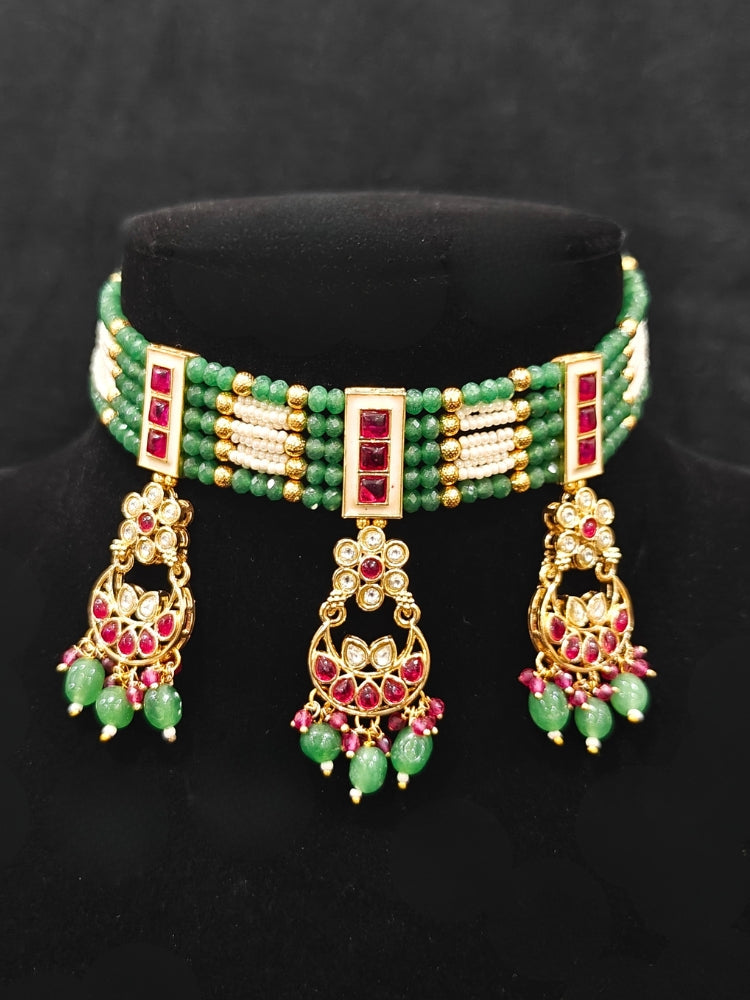 Close-up of an ornate traditional (Gold Polish) Green and Pink  Choker jewellery set and earrings and maangtikka with Pearls, Beads, Pink Colored Stones, Bandhai Work, Tumble Beads. Mehendi ceremony look completed with a handcrafted Colored Stone jewelry set. Woman styling a vibrant Colored Stone necklace with a festive saree.