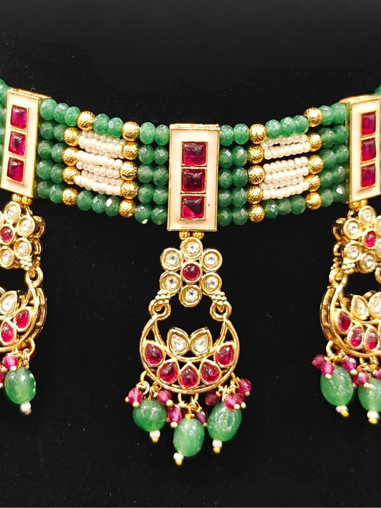 Close-up of an ornate traditional (Gold Polish) Green and Pink  Choker jewellery set and earrings and maangtikka with Pearls, Beads, Pink Colored Stones, Bandhai Work, Tumble Beads. Mehendi ceremony look completed with a handcrafted Colored Stone jewelry set. Woman styling a vibrant Colored Stone necklace with a festive saree.
