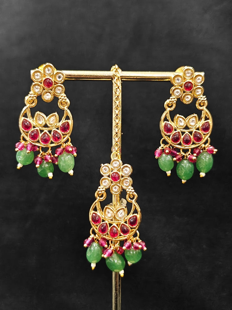 Close-up of an ornate traditional (Gold Polish) Green and Pink  Choker jewellery set and earrings and maangtikka with Pearls, Beads, Pink Colored Stones, Bandhai Work, Tumble Beads. Mehendi ceremony look completed with a handcrafted Colored Stone jewelry set. Woman styling a vibrant Colored Stone necklace with a festive saree.