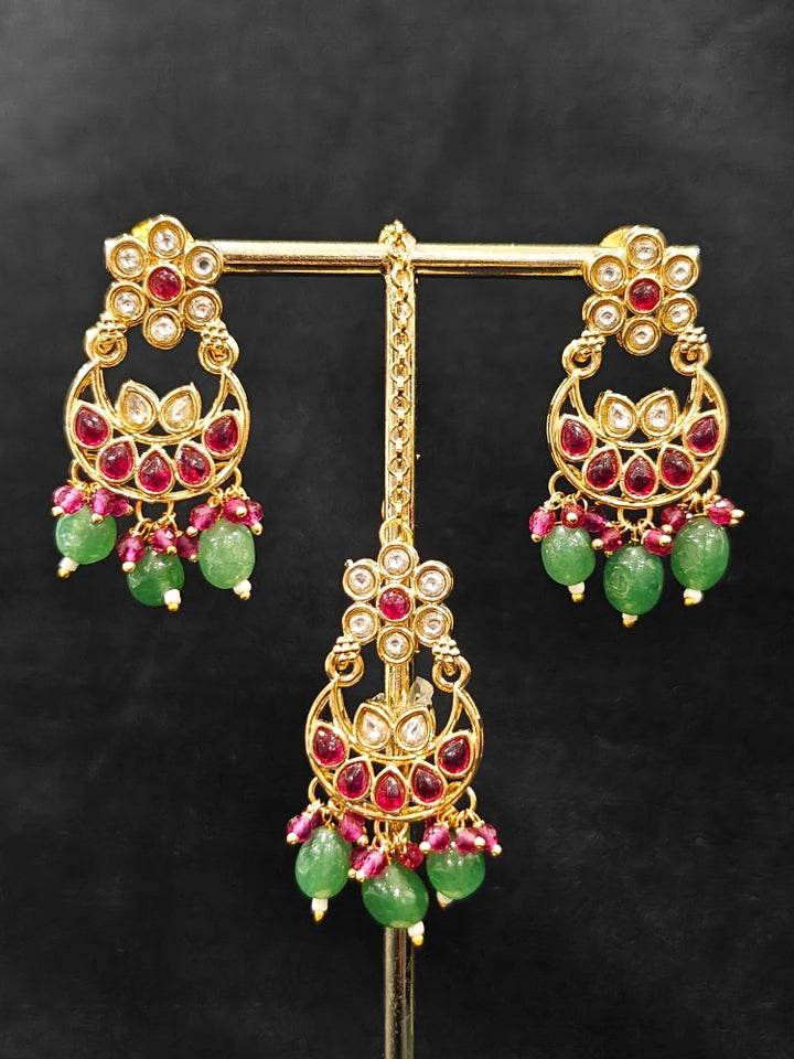 Close-up of an ornate traditional (Gold Polish) Green and Pink  Choker jewellery set and earrings and maangtikka with Pearls, Beads, Pink Colored Stones, Bandhai Work, Tumble Beads. Mehendi ceremony look completed with a handcrafted Colored Stone jewelry set. Woman styling a vibrant Colored Stone necklace with a festive saree.