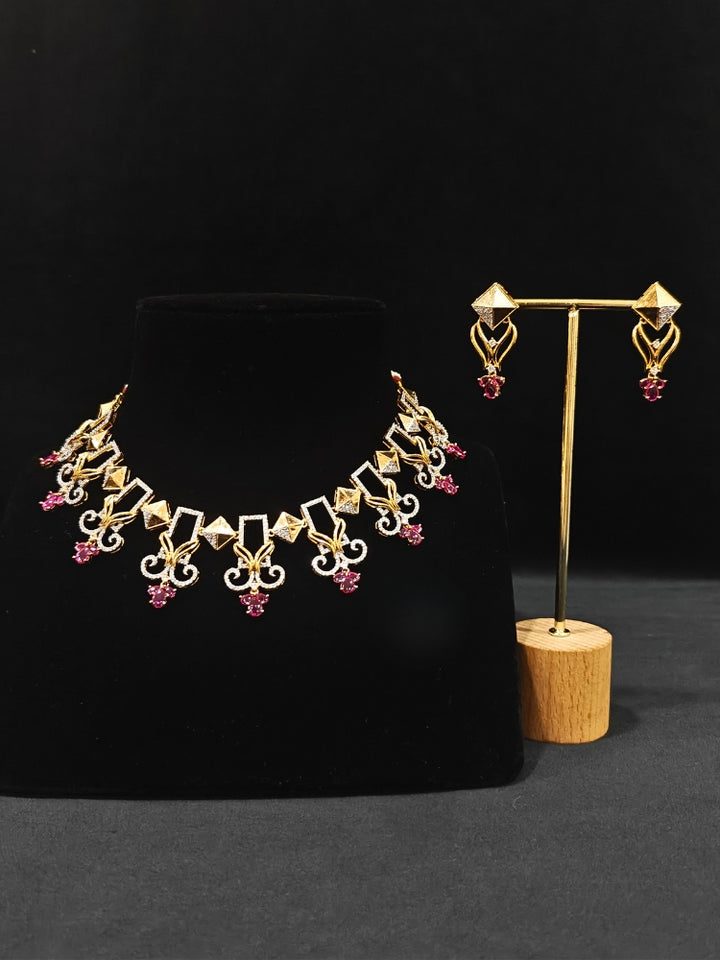 Close-up of an ornate Indo-western American Diamond Ruby Pink Gold Collar jewellery set and earrings with American Diamond and Ruby Pink Colored Stones. Party wear outfit completed with a lightweight American diamond necklace. 