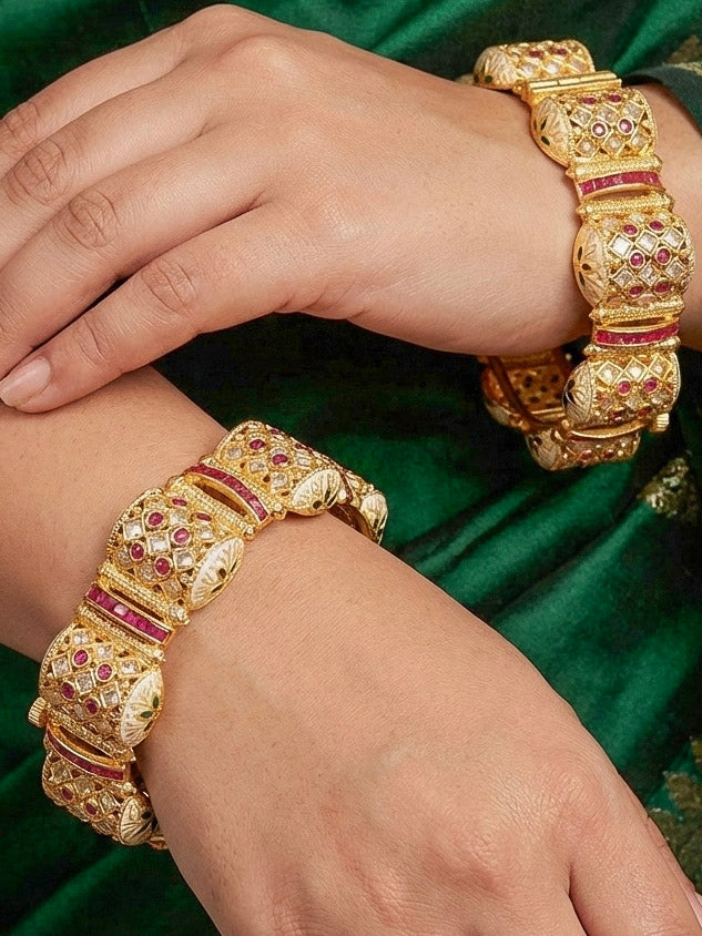 Close-up of a woman wearing an ornate traditional Rajwadi gold Bangle with Pink Colored Stone and Meenakari. Luxury artificial Rajwadi bangles styled for a wedding function. Close-up of artificial  Rajwadi and Meenakari bangles with detailed design.