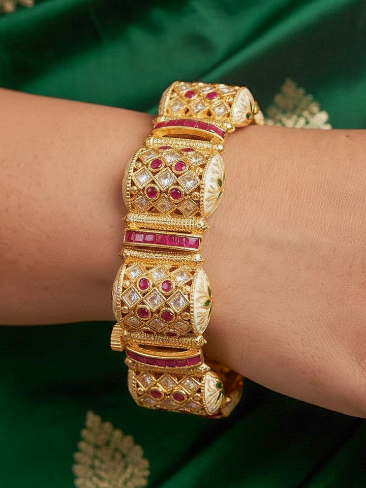 Close-up of a woman wearing an ornate traditional Rajwadi gold Bangle with Pink Colored Stone and Meenakari. Luxury artificial Rajwadi bangles styled for a wedding function. Close-up of artificial  Rajwadi and Meenakari bangles with detailed design.