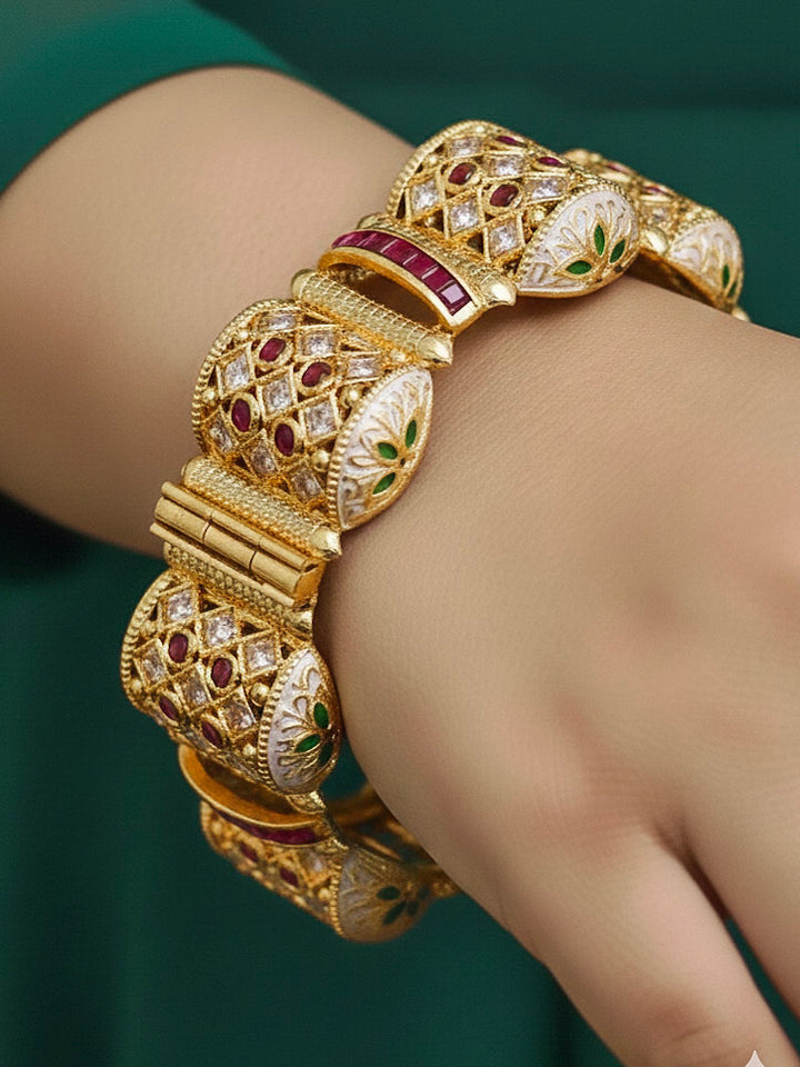 Close-up of a woman wearing an ornate traditional Rajwadi gold Bangle with Pink Colored Stone and Meenakari. Luxury artificial Rajwadi bangles styled for a wedding function. Close-up of artificial  Rajwadi and Meenakari bangles with detailed design.