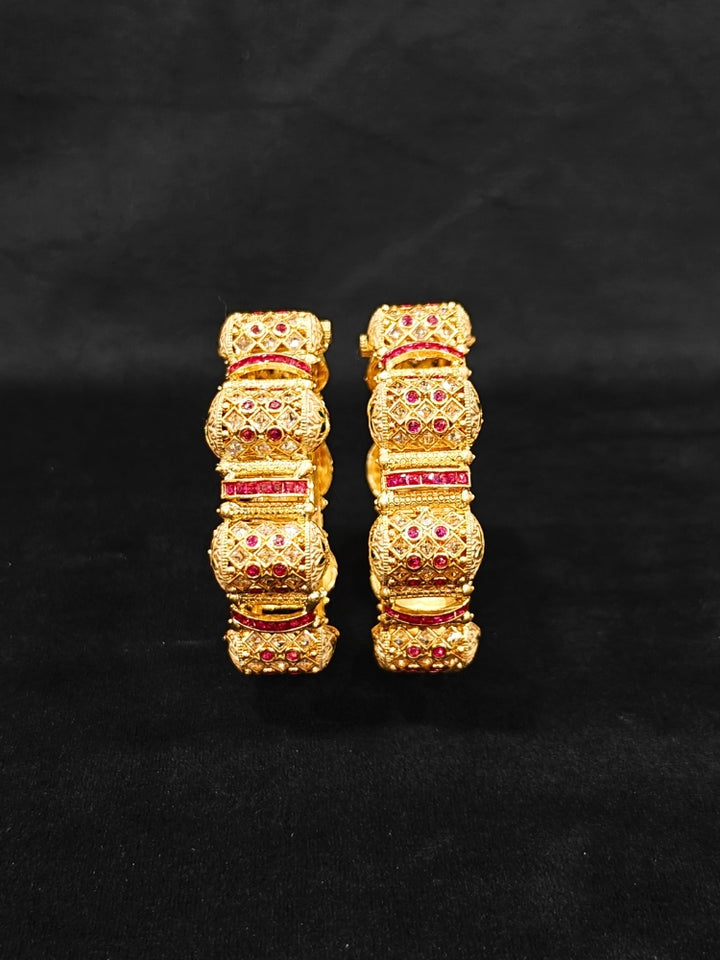 Close-up of an ornate traditional Rajwadi gold Bangle with Pink Colored Stone and Meenakari. Luxury artificial Rajwadi bangles styled for a wedding function. Close-up of artificial  Rajwadi and Meenakari bangles with detailed design.