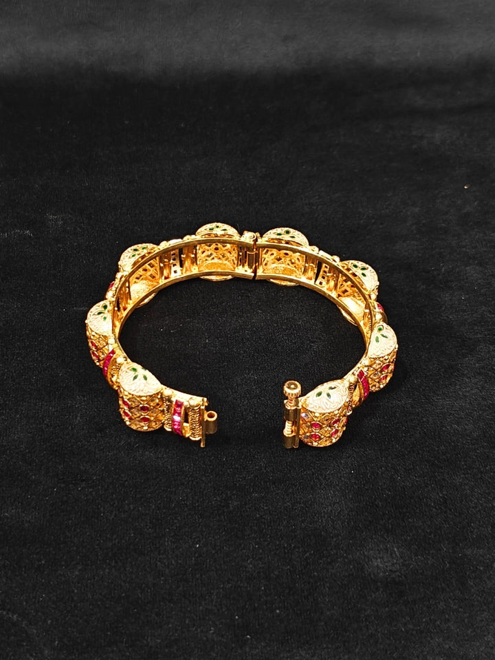 Close-up of an ornate traditional Rajwadi gold Bangle with Pink Colored Stone and Meenakari. Luxury artificial Rajwadi bangles styled for a wedding function. Close-up of artificial  Rajwadi and Meenakari bangles with detailed design.