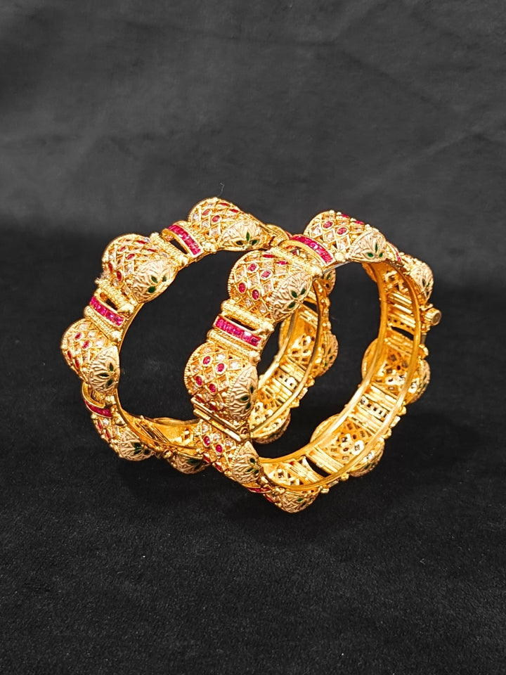 Close-up of an ornate traditional Rajwadi gold Bangle with Pink Colored Stone and Meenakari. Luxury artificial Rajwadi bangles styled for a wedding function. Close-up of artificial  Rajwadi and Meenakari bangles with detailed design.