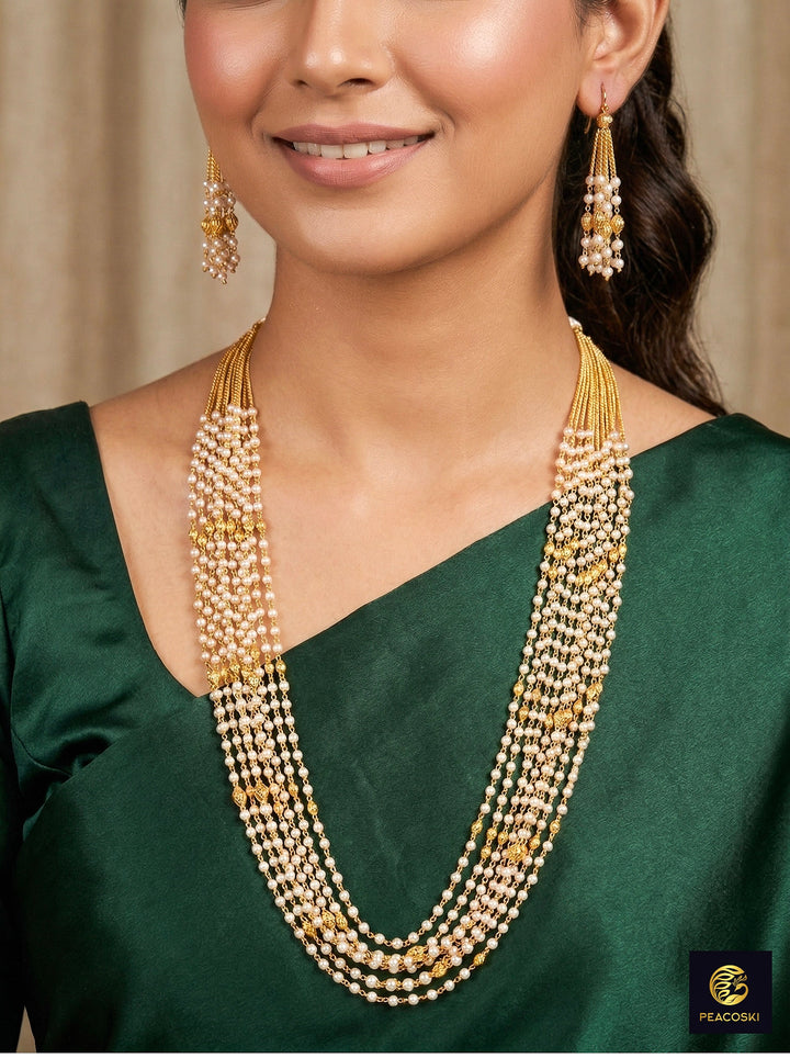 Close-up of a woman wearing an ornate traditional White Pearl Long Jewellery Set and Earrings with Pearl. Mehendi function outfit styled with a lightweight Pearl necklace. Festive saree look completed with a handcrafted Pearl necklace.