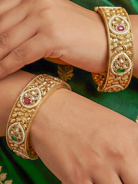 Close-up of a woman wearing an ornate traditional Rajwadi gold Bangle with Bandhai Work, Red & Green Colored Stone and Pearls. Festive celebration look enhanced with statement artificial  Rajwadi bangles. Luxury artificial Rajwadi bangles styled for a wedding function.