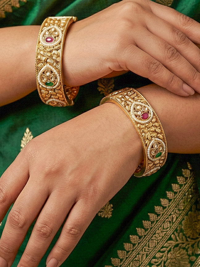 Close-up of a woman wearing an ornate traditional Rajwadi gold Bangle with Bandhai Work, Red & Green Colored Stone and Pearls. Festive celebration look enhanced with statement artificial  Rajwadi bangles. Luxury artificial Rajwadi bangles styled for a wedding function.