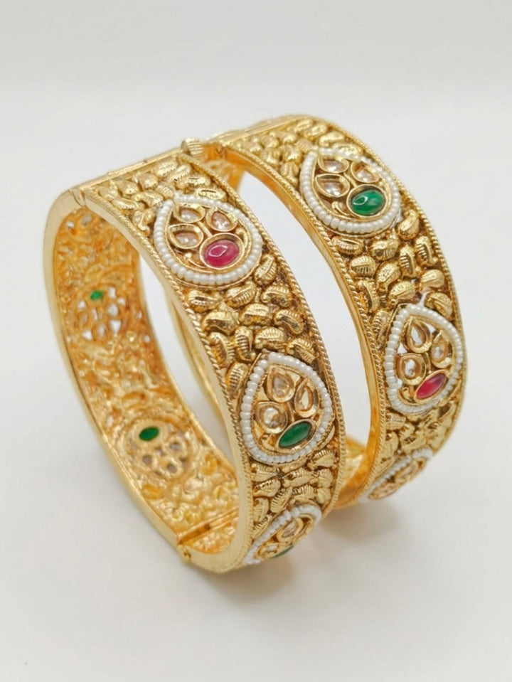 Close-up of an ornate traditional Rajwadi gold Bangle with Bandhai Work, Red & Green Colored Stone and Pearls. Festive celebration look enhanced with statement artificial  Rajwadi bangles. Luxury artificial Rajwadi bangles styled for a wedding function.