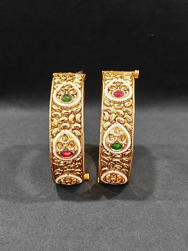 Close-up of an ornate traditional Rajwadi gold Bangle with Bandhai Work, Red & Green Colored Stone and Pearls. Festive celebration look enhanced with statement artificial  Rajwadi bangles. Luxury artificial Rajwadi bangles styled for a wedding function.